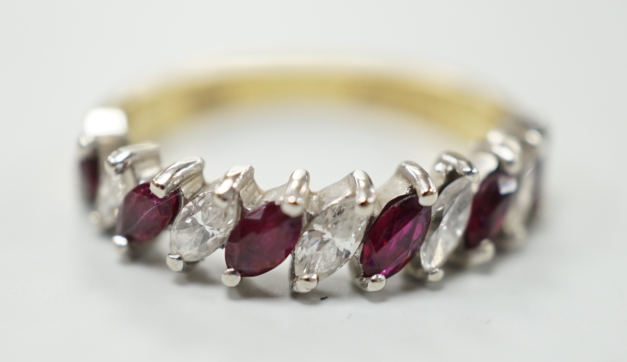 A modern 18ct gold and eleven stone marquise cut ruby and diamond set half hoop ring, size L, gross weight 3.5 grams.